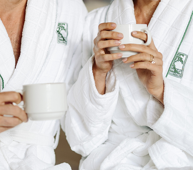 Guests at The Lodge at Torrey Pines enjoying a morning coffee on their deck wearing luxury robes, part of the luxury room amenities at this five diamond resort in La Jolla, CA.