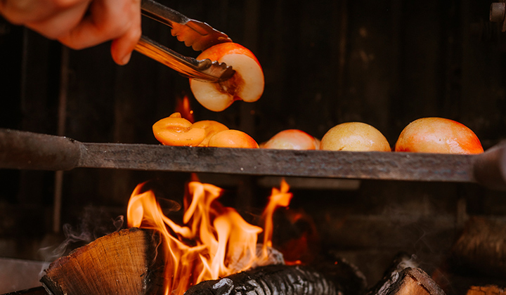 Apples being roasted over a fire at the Playing with Fire Dinner Series featuring Chef Sydney Imlay, Chef David Sim and Coronado Brewing Company at The Grill at Torrey Pines