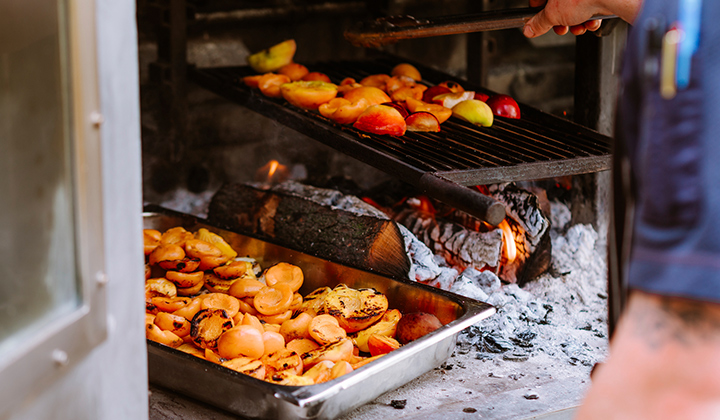 Chef grilling apples over a wood fire at the Playing with Fire Dinner Series featuring Chef Trey Foshee, Chef Jason Knibb, Chef Jeff Jackson and Burgeon Beer Company at The Grill at Torrey Pines in La Jolla